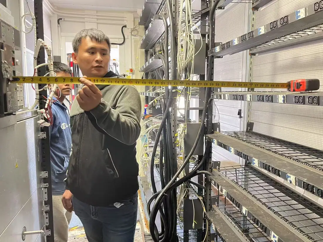 Technician measuring rack and power-distribution clearances inside a retrofit program