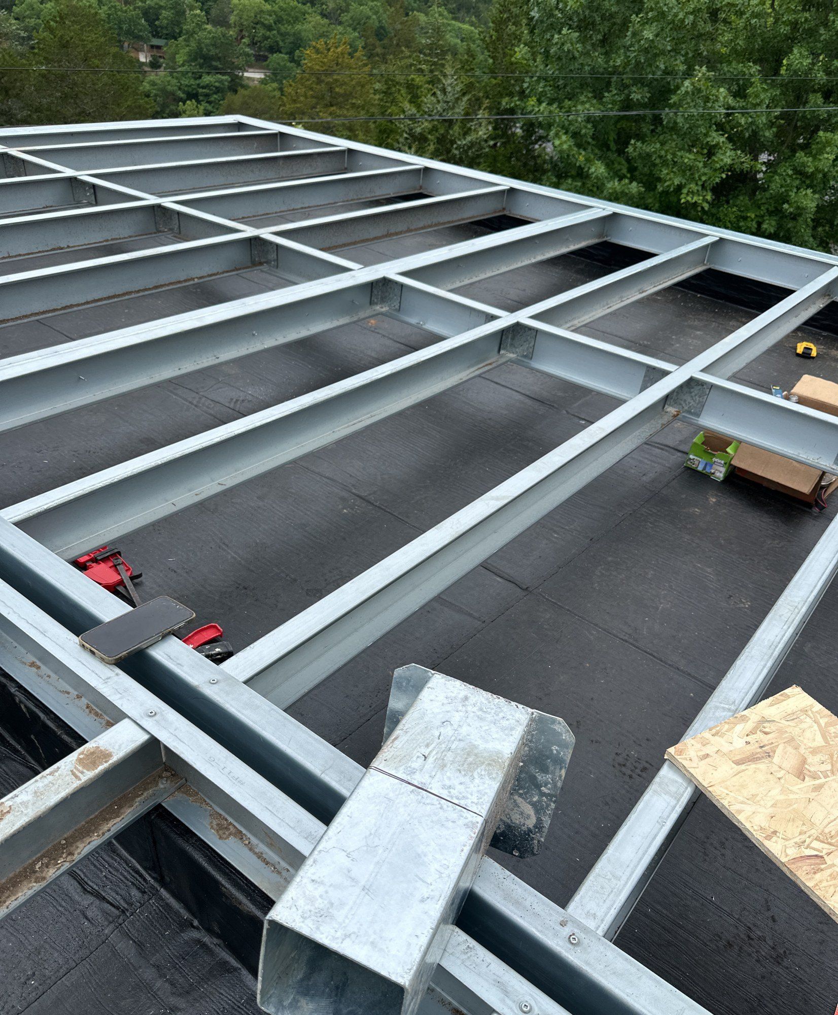Galvanized steel deck frame set out over a black membrane, with fixings and offcuts on the surface, 21 May 2026