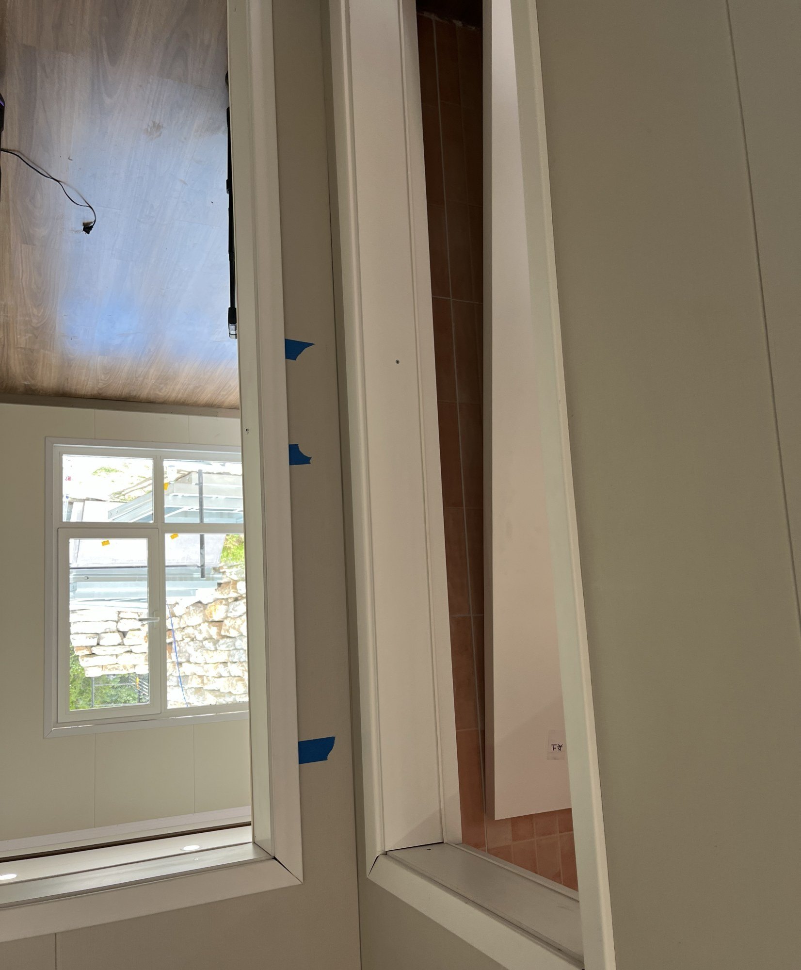 Finished interior room with white wall panels, a window and an open doorway to a second room, 12 July 2026