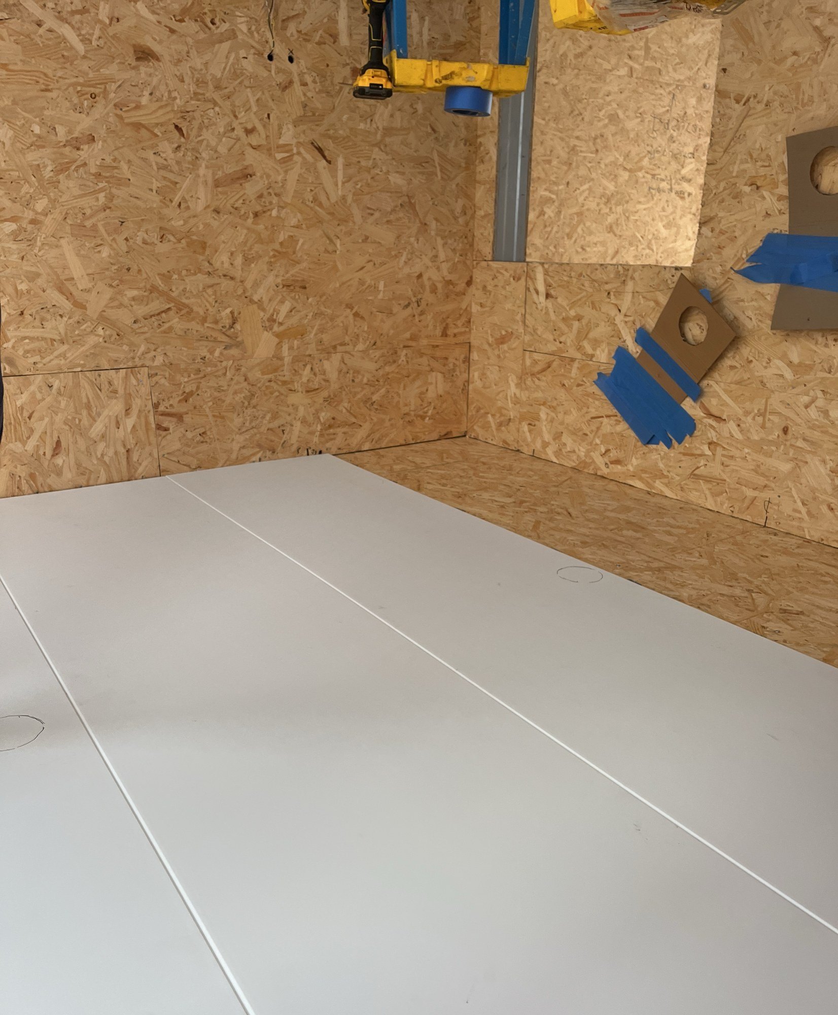 Large white floor panel laid across a room lined with oriented strand board sheathing, 24 July 2026
