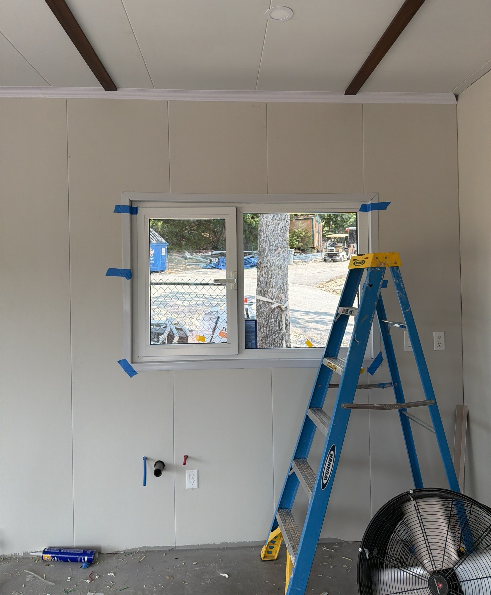White panelled room with a dark ceiling beam detail, a window and a step ladder standing in the middle, 29 July 2026