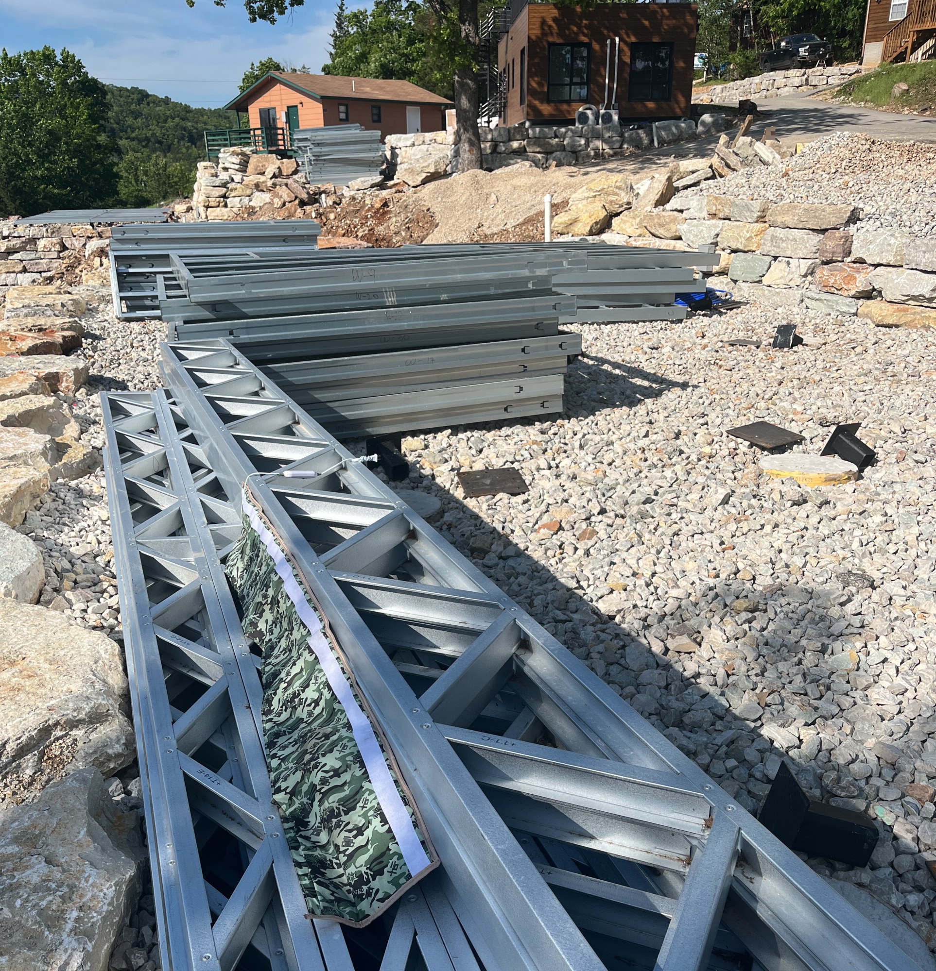 Open-web steel joists staged on the ground next to the pier foundations, 4 May 2026
